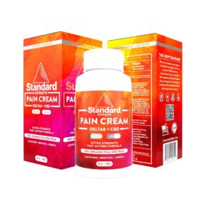 A bottle of Standard Extracts Pain Cream (Delta 8 + CBD) is displayed in front of two product boxes with red and orange gradient designs and white text, reflecting the brand's dedication to the cleanest wellness and vaping products.