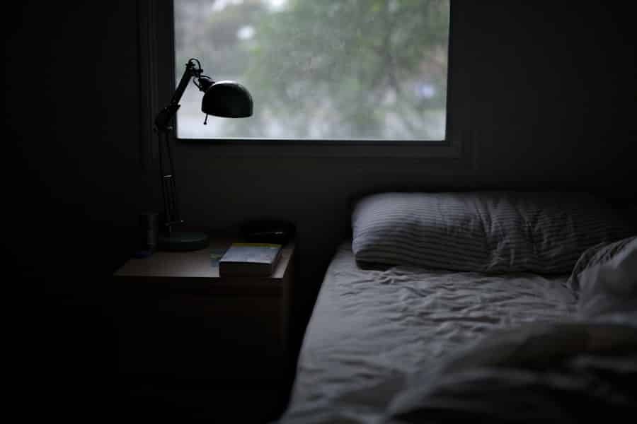 Bed beside a soft task lamp, where an evening hemp routine ends