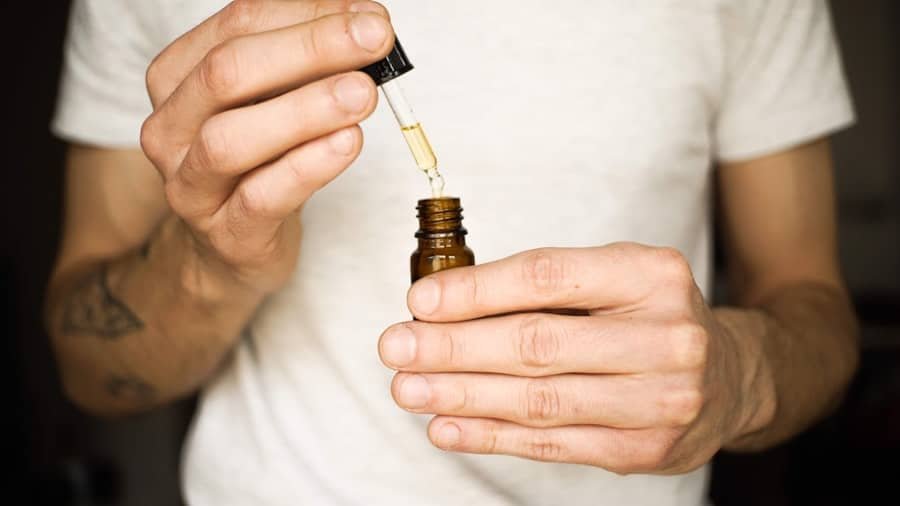 Person holding a dropper bottle of CBD tincture for a daily routine
