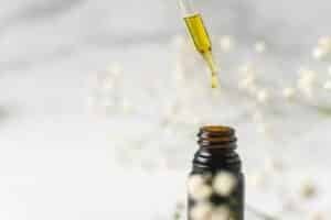 Dropper of hemp oil above an amber bottle, CBD and CBN tincture concept