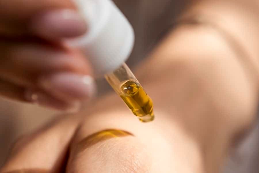 Person holding a dropper of full spectrum hemp extract with terpenes