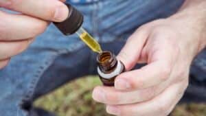 Hands filling a dropper from a CBD tincture bottle