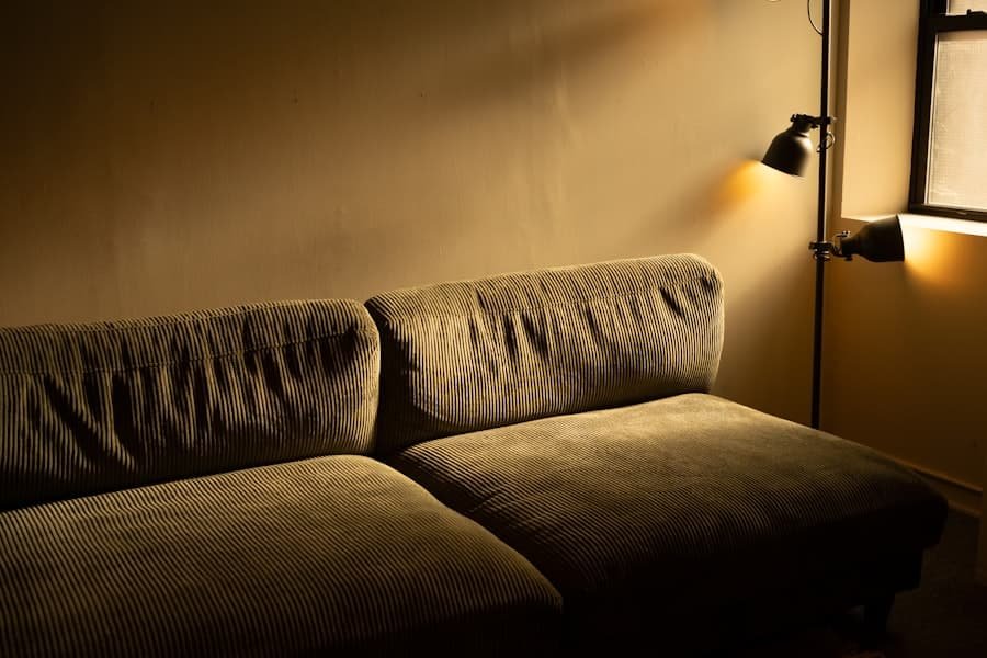 A corduroy sofa lit by a warm floor lamp in a quiet evening room