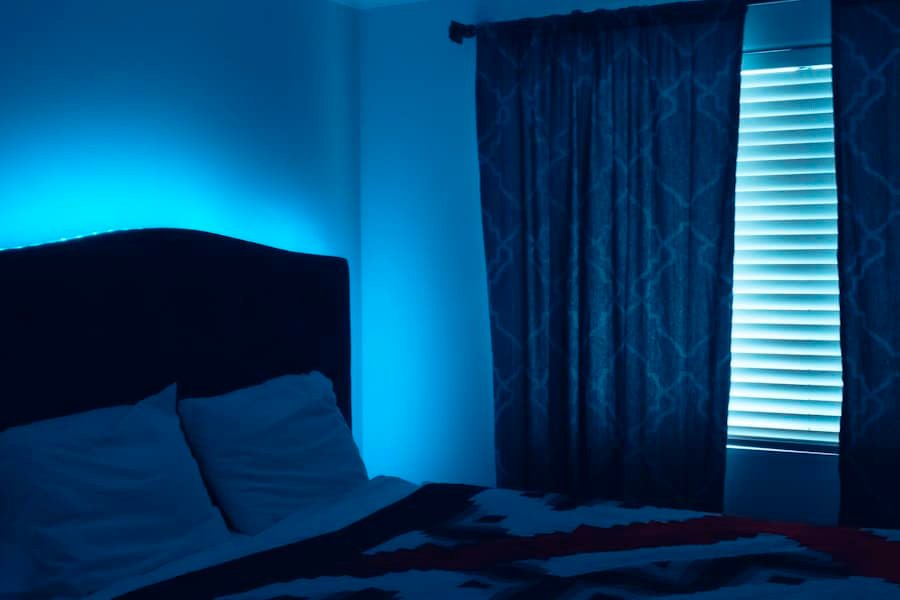 A made bed beside a curtained window in cool evening light