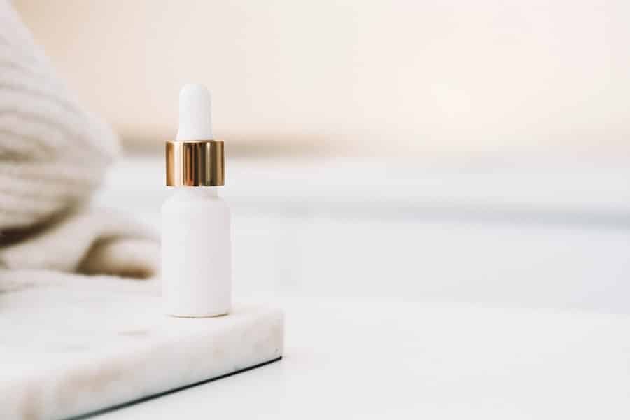 A plain white dropper bottle on a marble surface