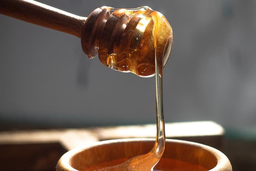 Thick golden liquid drizzling from a wooden dipper into a bowl