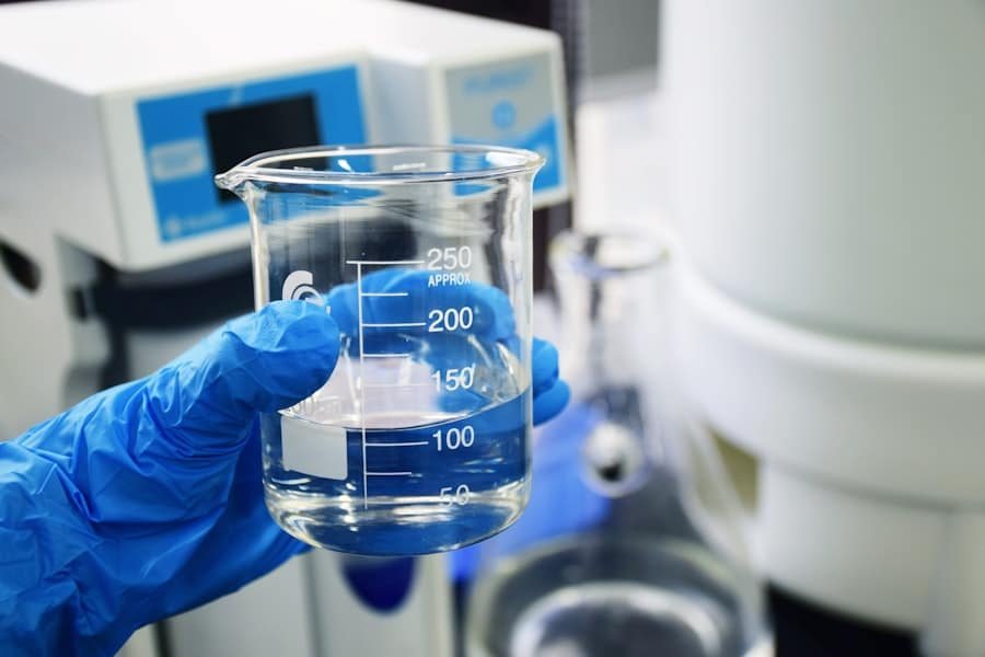 A gloved hand holding a laboratory beaker of clear liquid