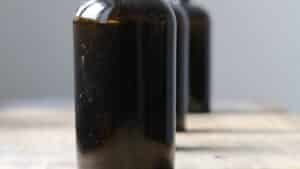 An unlabeled dark amber glass bottle on a wooden surface