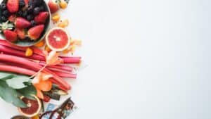 A flat lay of sliced fruit and berries on a white surface