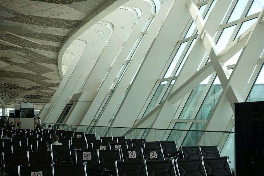 Rows of seats beside tall slanted windows in a bright airport terminal
