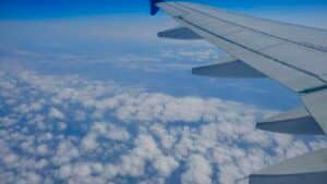 An airplane wing seen from a window seat above scattered clouds