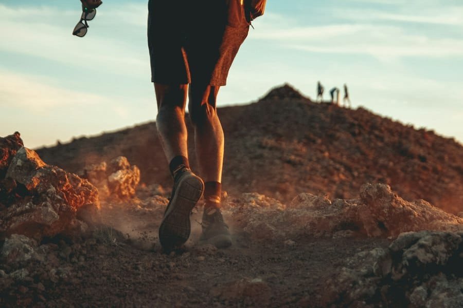 A runner's legs mid-stride on a dusty mountain trail