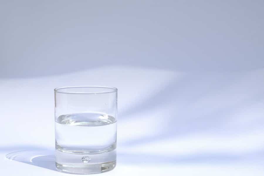 A clear glass of water on a white surface in soft daylight