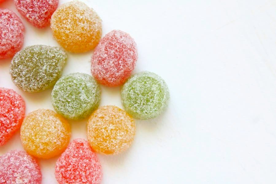Sugar-coated gummies in soft colors on a white surface
